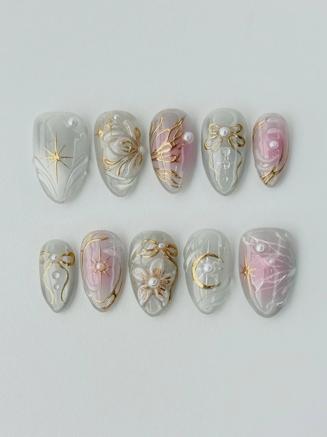 Handmade press-on nails with white, gold, and pearl celestial moon and star designs.