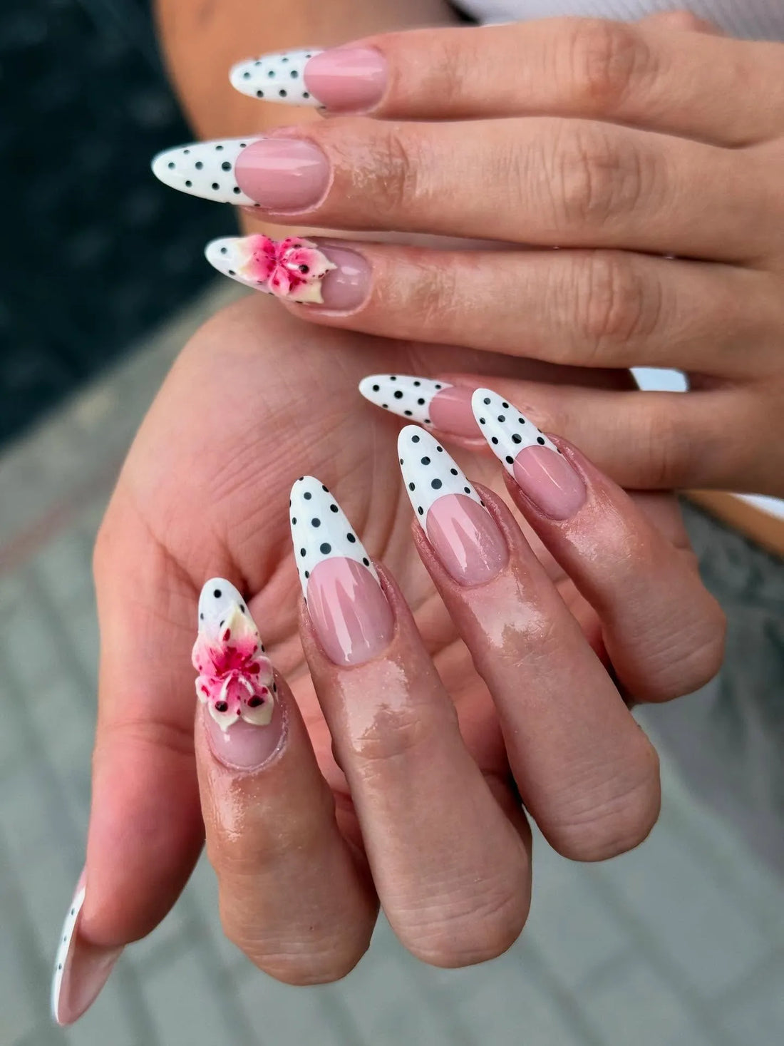 Handmade press-on nails with white polka dot French tips and pink floral accents.