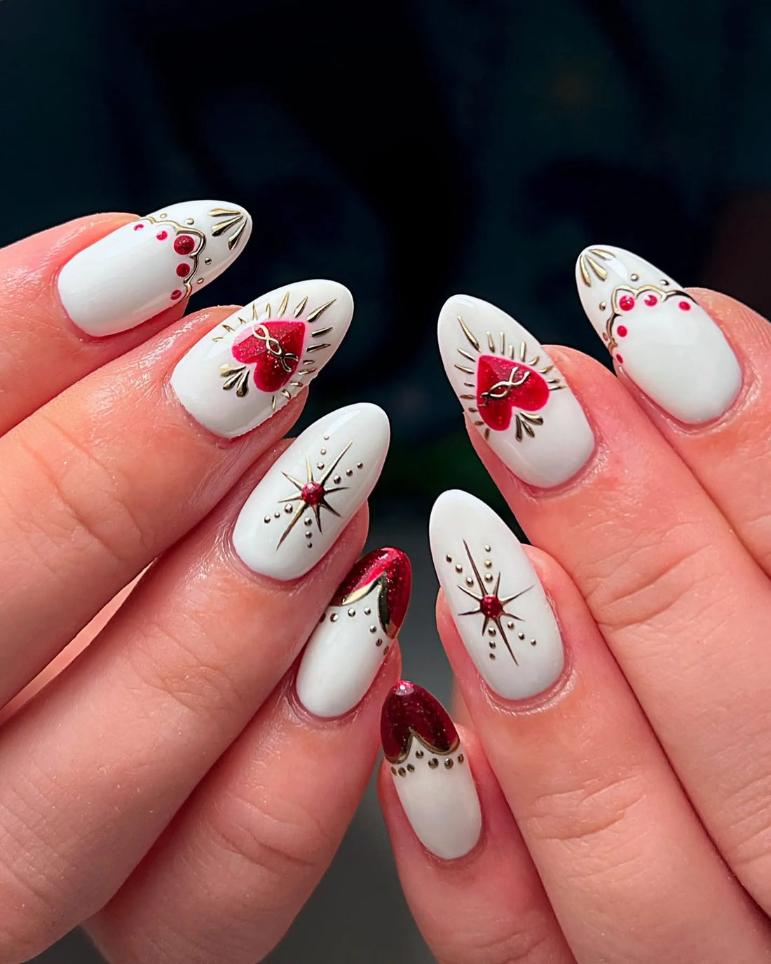 White press-on nails with red heart accents, gold filigree, and gemstone details.