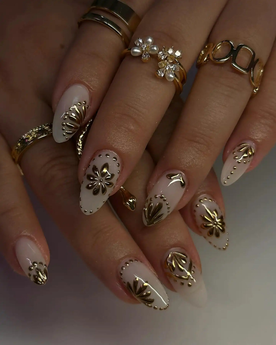 Hand wearing white and gold 3D floral accent glossy press-on nails with elegant nail art.