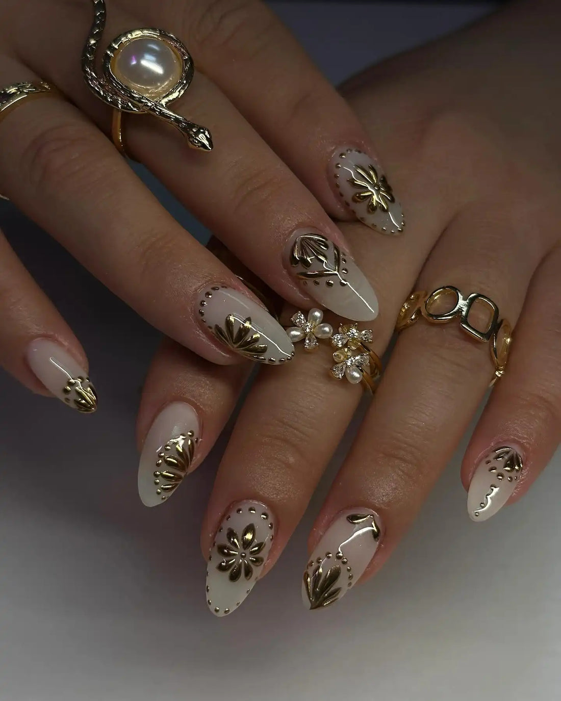Hand wearing white and gold 3D floral accent glossy press-on nails with elegant nail art.