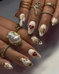 Hand displaying white and gold handmade press-on nails with floral and heart designs