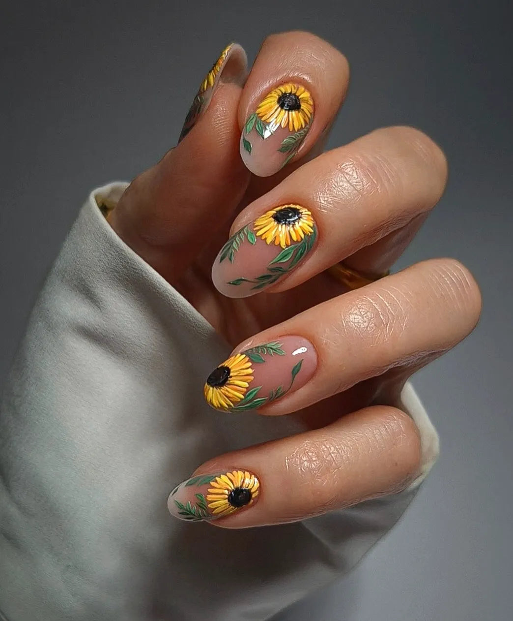 Hand with handmade press-on nails featuring yellow sunflower floral design