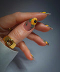 Hand with handmade yellow sunflower summer floral press-on nails, close-up design detail