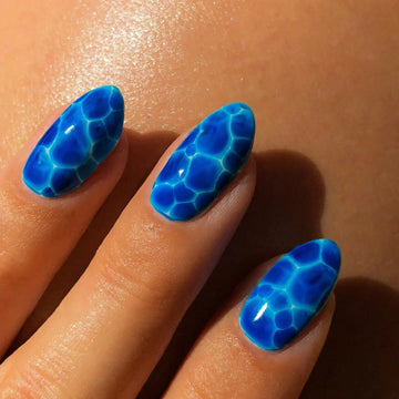 Hand with blue 3D aura press-on nails featuring a vibrant, water-inspired design