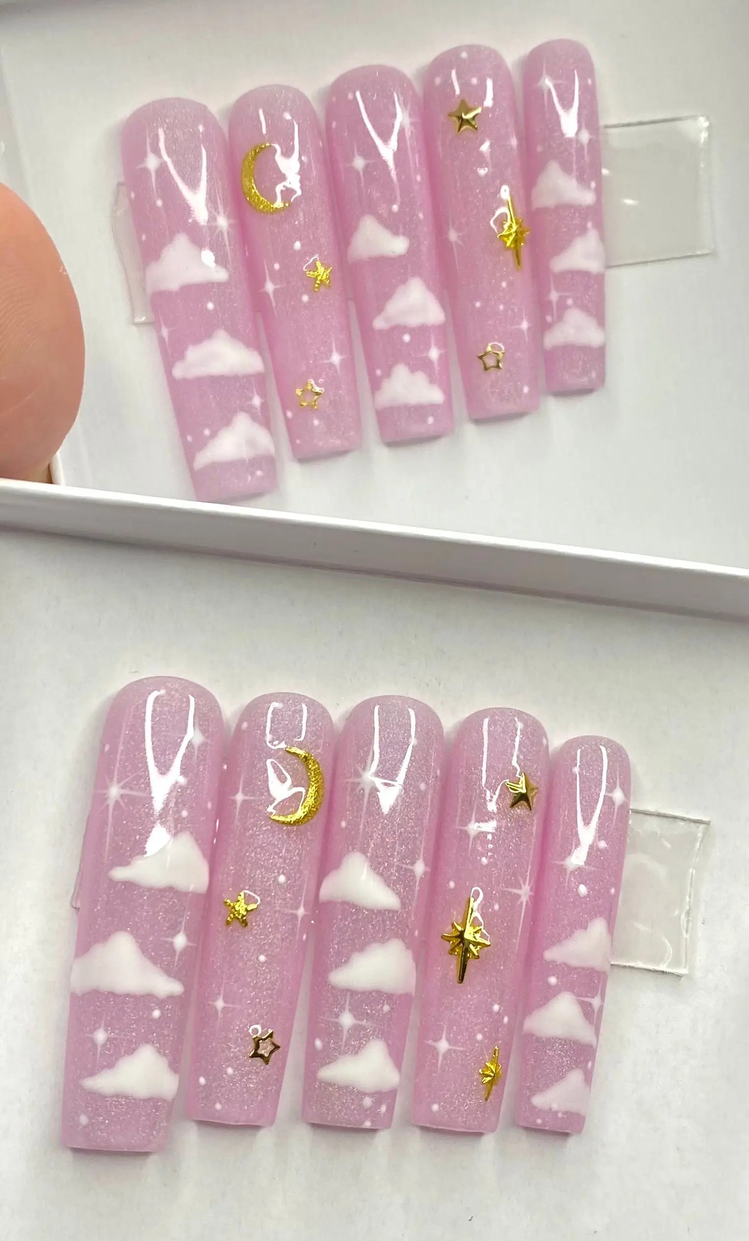 Pink press-on nails with white clouds and gold moon and star designs