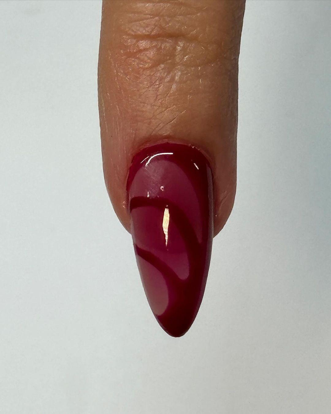 Almond-shaped red and nude press-on nails with glossy finish and accent gems