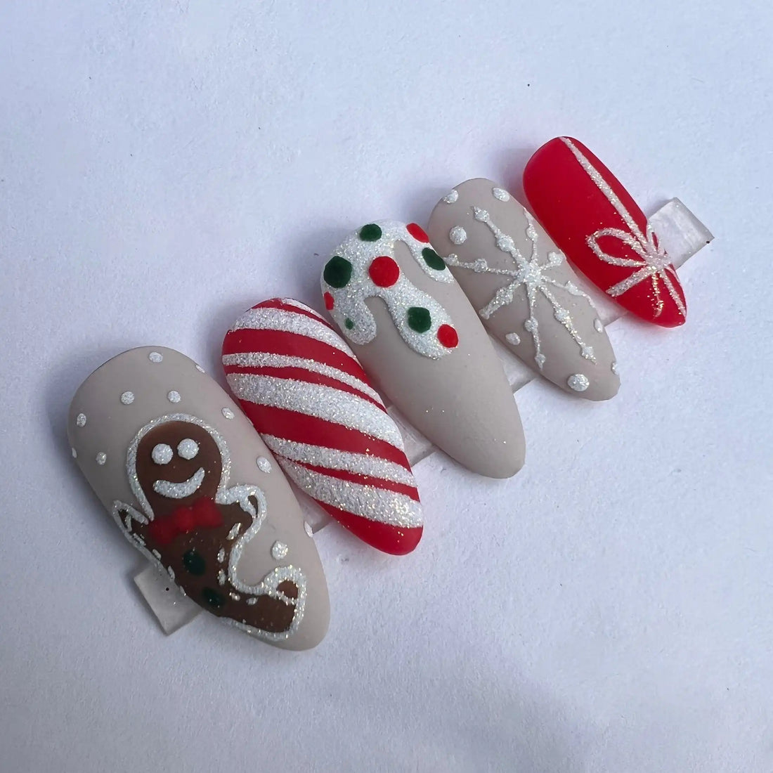 Handmade Christmas press-on nails with gingerbread man, candy cane, and festive designs.