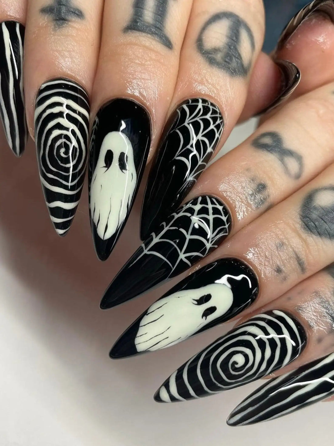 Handmade black press-on nails with white ghost, spiderweb, and swirl Halloween designs