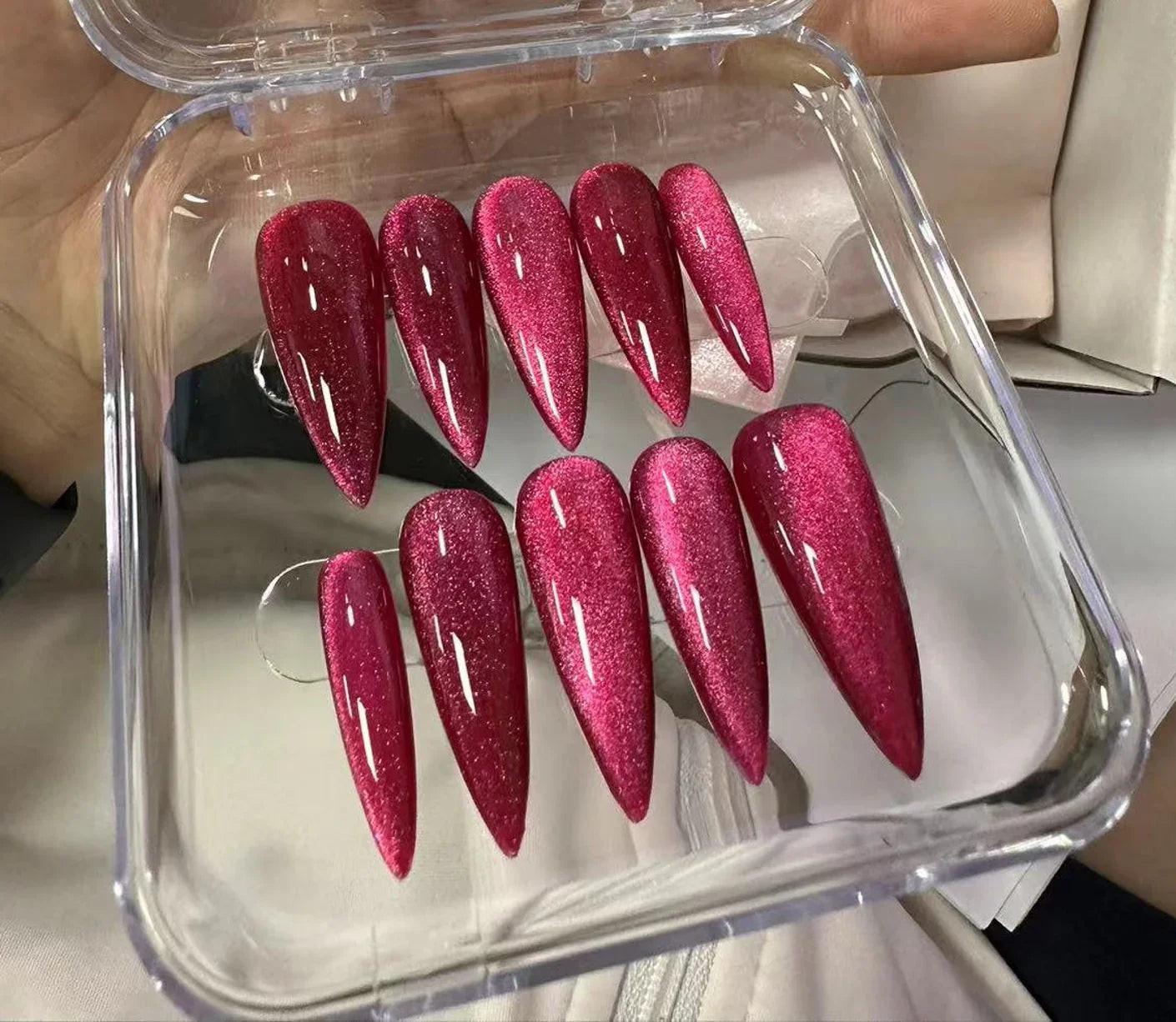 Glossy raspberry red glitter press-on nails with cat eye effect in a clear case