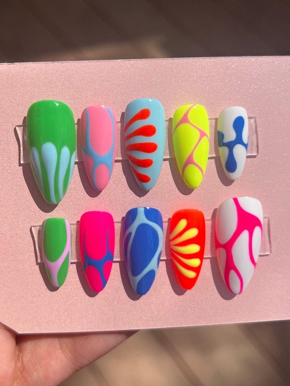Handmade colorful press-on nails set with abstract and wavy designs on display card
