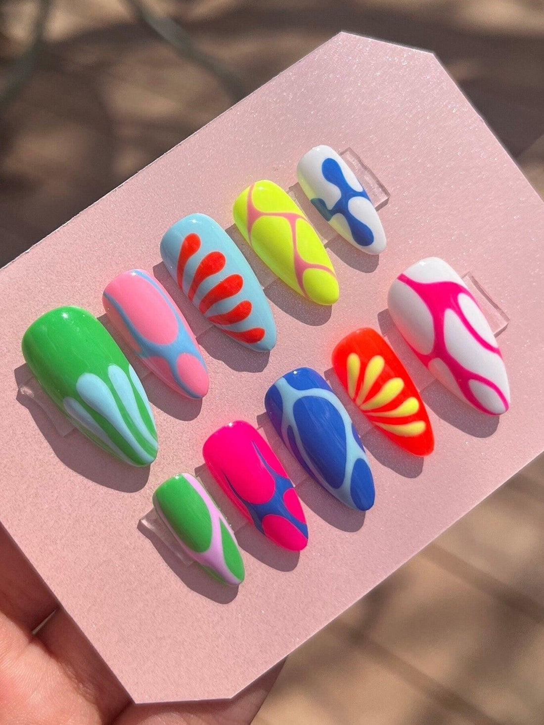 Handmade colorful press-on nails set with abstract and wavy designs on display card