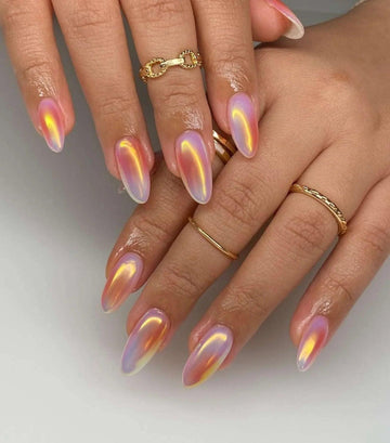 Hand with long almond-shaped iridescent press-on nails, gradient pastel design, gold rings