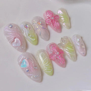 Handmade iridescent press-on nails with 3D floral, butterfly, and pearl designs on white surface